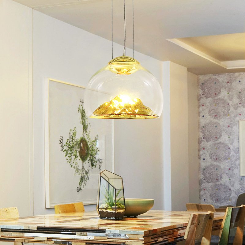 Transform your space with the Modern Electroplated Glass Pendant Lamp, a sophisticated lighting solution that blends contemporary design with artistic flair. Featuring a sleek, electroplated golden glass finish and a unique Nordic mountain-inspired design, this lamp adds a touch of elegance to any room. Crafted from high-quality glass and iron, it provides durable, energy-efficient lighting with included LED bulbs. The adjustable steel cables allow for customizable height, making it perfect for dining areas, living rooms, bedrooms, restaurants, hotels, or offices. Available in clear and golden or clear and silver finishes, this pendant lamp enhances any interior with style and functionality. Elevate your decor today!