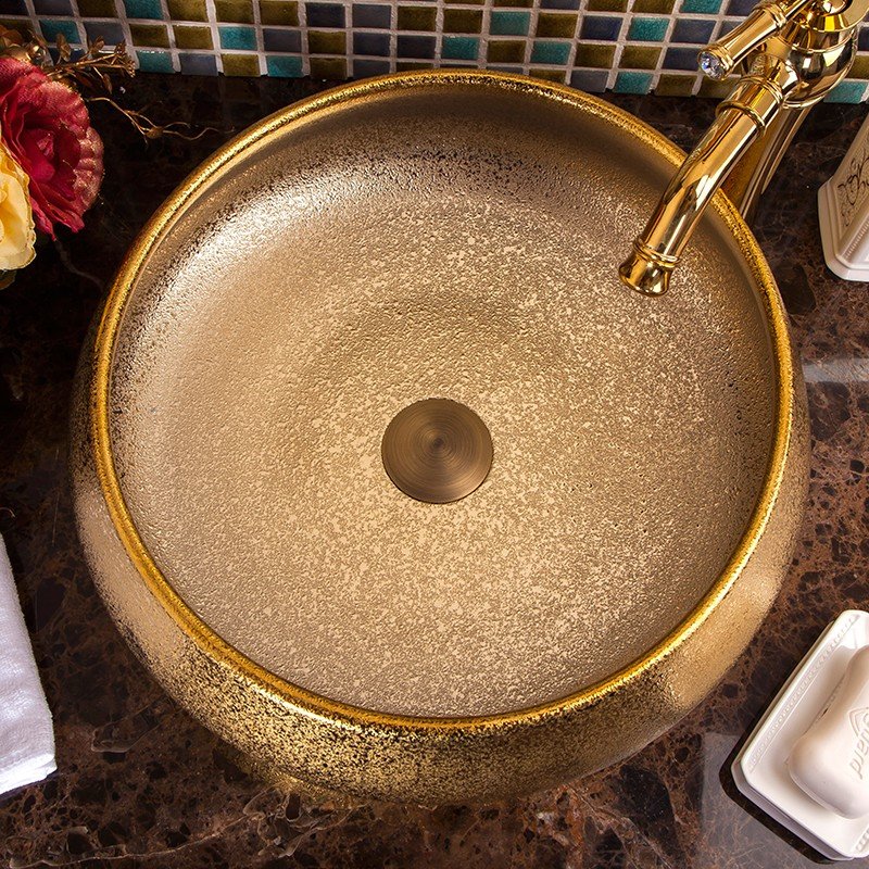 Elevate your bathroom with our Luxury Gold Glazed Ceramic Bathroom Basin, a stunning hand-made vessel sink that exudes elegance and sophistication. Featuring a luxurious gold glaze finish and unique oval shape, this high-quality ceramic basin is designed to add a touch of opulence to any bathroom. Its durable, easy-to-clean surface ensures lasting beauty, while its versatile design complements both contemporary and traditional decor styles. Make a statement with this exquisite bathroom upgrade—order yours today and transform your space into a luxurious retreat.